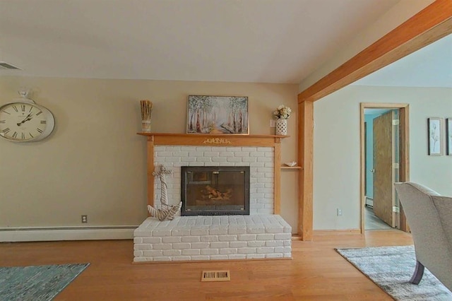 16172 Crest Dr, Linden, MI 48451 - living room featuring wood finished floors, baseboard heating, a brick fireplace, and baseboards