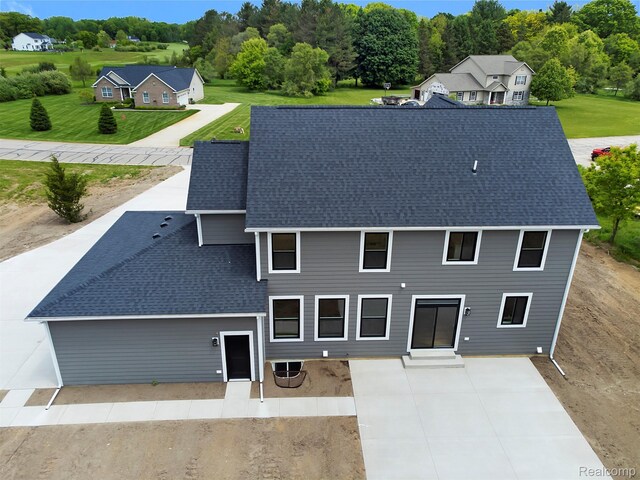 3097 Gecko Trl, Pinckney, MI 48169 - back of property featuring a patio area, roof with shingles, and a lawn