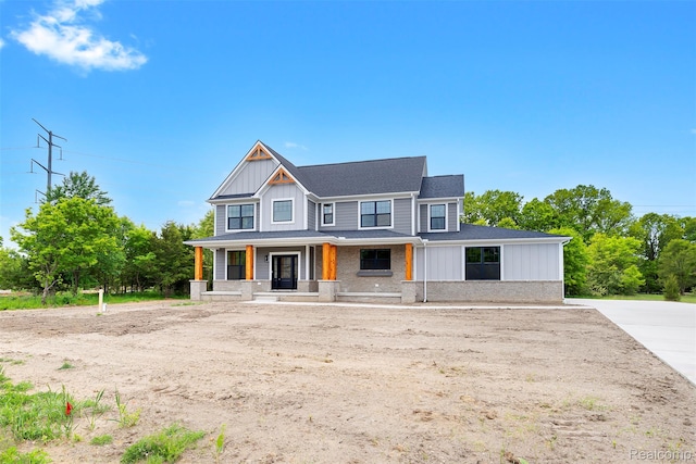 3097 Gecko Trl, Pinckney, MI 48169 - view of front facade with board and batten siding, a porch, and a shingled roof
