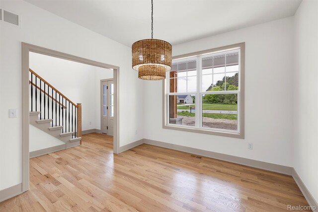 3097 Gecko Trl, Pinckney, MI 48169 - unfurnished dining area featuring a chandelier, light wood-type flooring, baseboards, and stairs