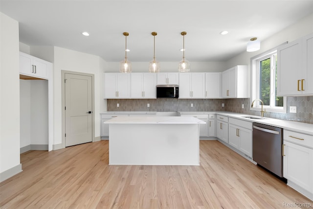 3097 Gecko Trl, Pinckney, MI 48169 - kitchen with appliances with stainless steel finishes, a sink, tasteful backsplash, white cabinetry, and light wood-type flooring