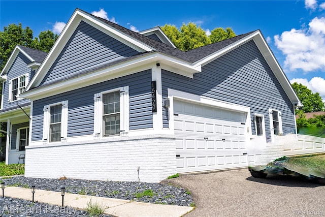 16429 E Horseshoe Trl, Linden, MI 48451 - view of side of property featuring an attached garage, asphalt driveway, and roof with shingles