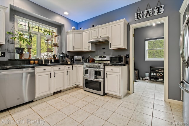 16429 E Horseshoe Trl, Linden, MI 48451 - kitchen with stainless steel appliances, under cabinet range hood, dark countertops, light tile patterned floors, and recessed lighting