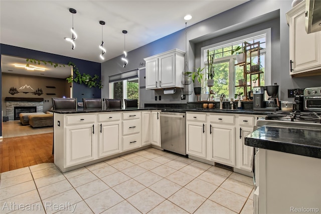 16429 E Horseshoe Trl, Linden, MI 48451 - kitchen featuring stainless steel dishwasher, a peninsula, dark countertops, light tile patterned flooring, and white cabinets