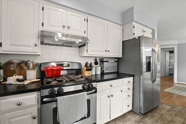 30139 Bentley St, Livonia, MI 48154 - kitchen featuring appliances with stainless steel finishes, under cabinet range hood, dark countertops, white cabinetry, and decorative backsplash