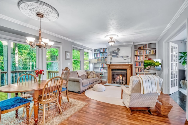 9180 Dicey St, Montague, MI 49437 - living room with light wood-style floors, a glass covered fireplace, a chandelier, crown molding, and built in shelves