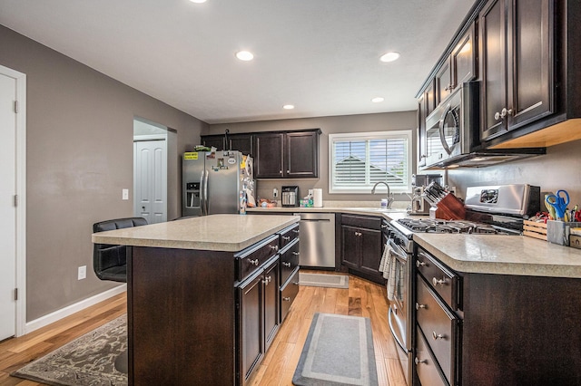 69218 Sundance Dr, Edwardsburg, MI 49112 - kitchen featuring stainless steel appliances, a sink, light wood finished floors, dark brown cabinetry, and light countertops