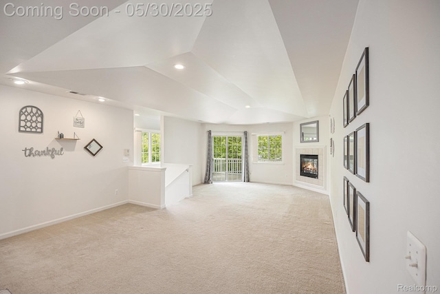 6769 Boulder Pointe Dr, Washington, MI 48094 - empty room featuring vaulted ceiling, baseboards, recessed lighting, light carpet, and a tile fireplace