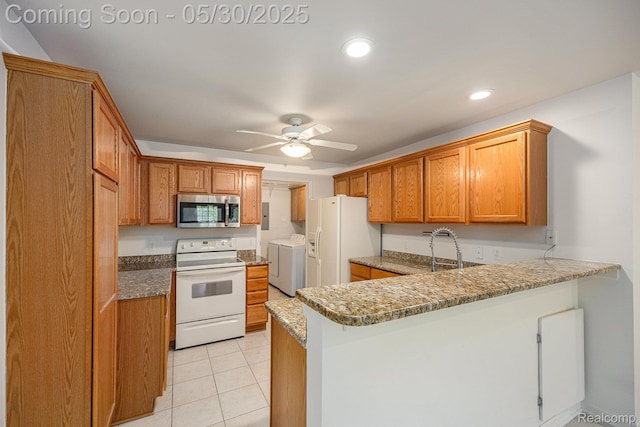 6769 Boulder Pointe Dr, Washington, MI 48094 - kitchen featuring white appliances, washer and clothes dryer, a peninsula, a ceiling fan, and brown cabinets