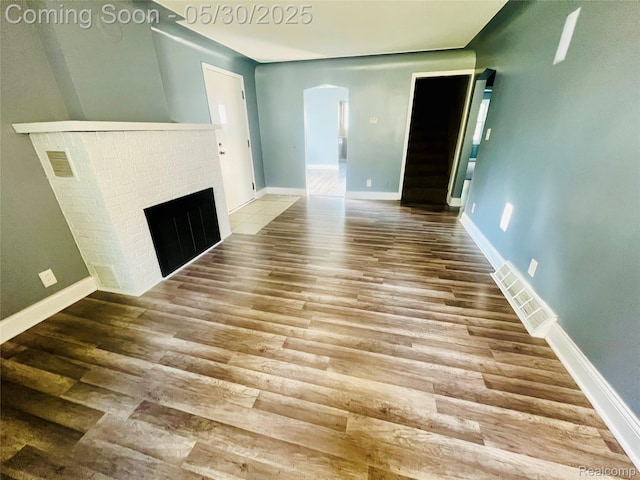 22380 Panama Ave, Sterling Heights, MI 48091 - unfurnished living room with wood finished floors, arched walkways, a fireplace, stairway, and baseboards