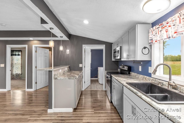 11943 Mulliken Rd, Mulliken, MI 48861 - kitchen with appliances with stainless steel finishes, a sink, wood finished floors, vaulted ceiling, and hanging light fixtures