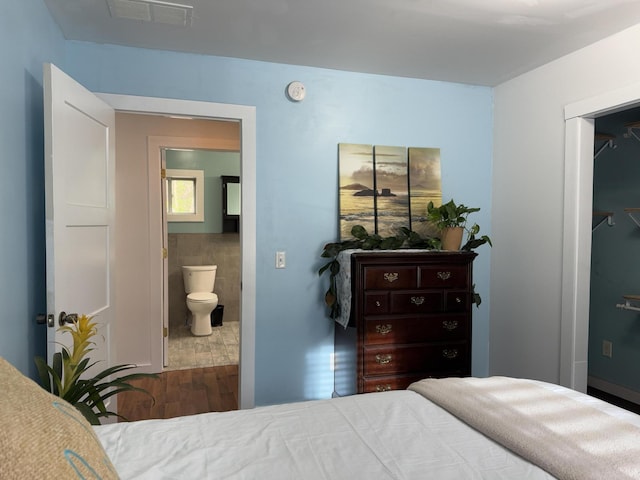 1581 W Lone Pine Dr, Baldwin, MI 49304 - bedroom featuring wood finished floors, tile walls, and ensuite bathroom