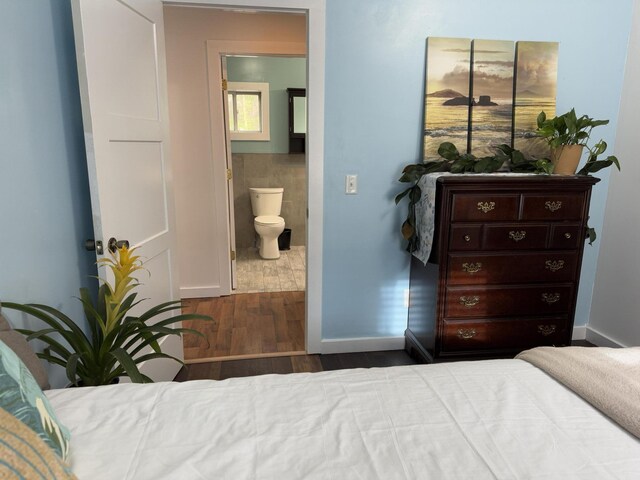 1581 W Lone Pine Dr, Baldwin, MI 49304 - bedroom featuring wood finished floors, ensuite bathroom, tile walls, and baseboards