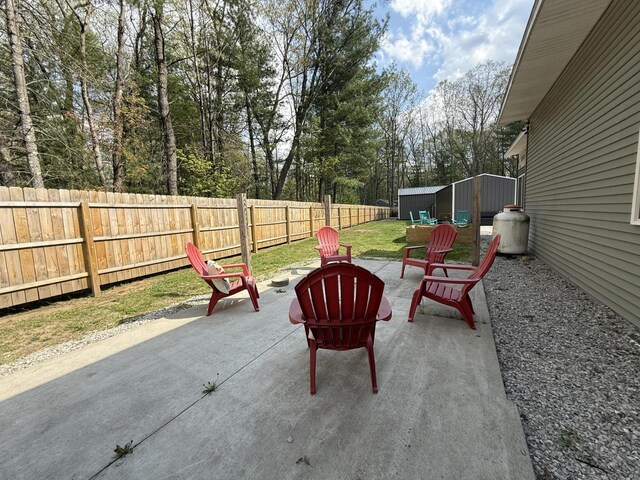 1581 W Lone Pine Dr, Baldwin, MI 49304 - fenced backyard featuring a patio, a fire pit, and view of wooded area
