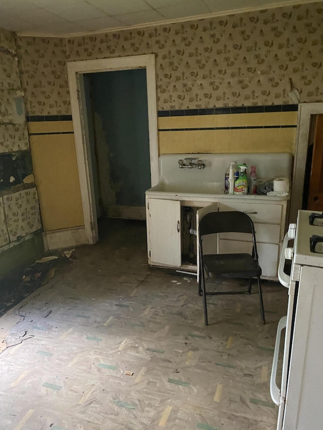 525 NE Eastern Ave NE, Grand Rapids, MI 49503 - kitchen with wallpapered walls, a wainscoted wall, white gas range oven, and tile counters
