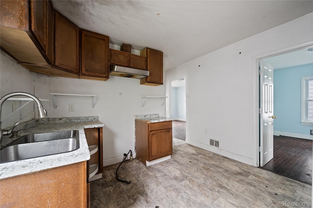 18666 Carrie St, Hamtramck, MI 48234 - kitchen with a sink, under cabinet range hood, brown cabinets, and light countertops