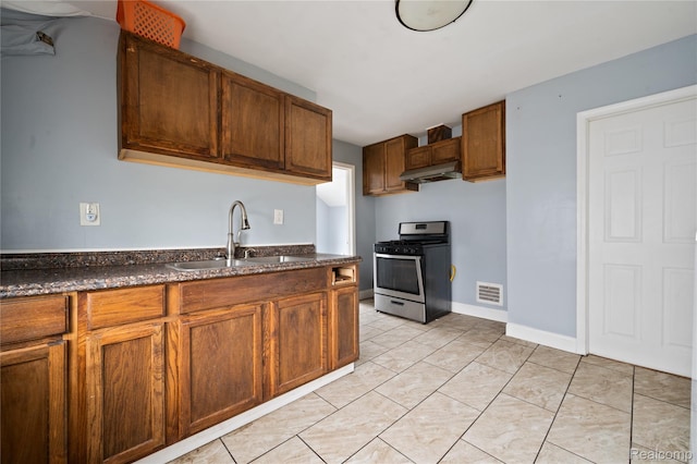 18666 Carrie St, Hamtramck, MI 48234 - kitchen with stainless steel gas range oven, a sink, under cabinet range hood, brown cabinets, and light tile patterned flooring