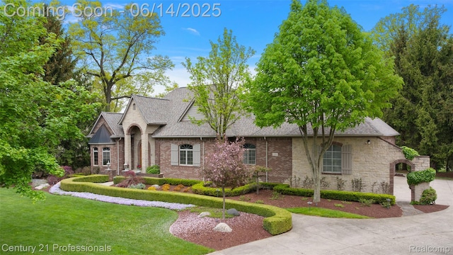 1181 Iroquois Trl, Oxford, MI 48371 - french country inspired facade featuring a shingled roof, brick siding, and a front yard