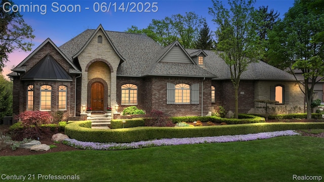 1181 Iroquois Trl, Oxford, MI 48371 - french country home featuring a yard, a shingled roof, brick siding, and a standing seam roof