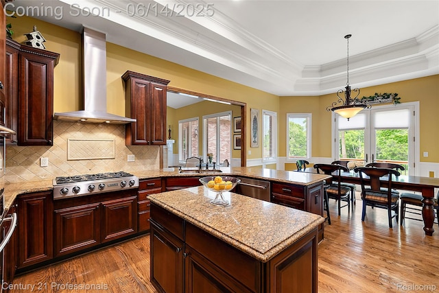 1181 Iroquois Trl, Oxford, MI 48371 - kitchen with wall chimney range hood, stainless steel appliances, light wood-style flooring, a center island, and a raised ceiling