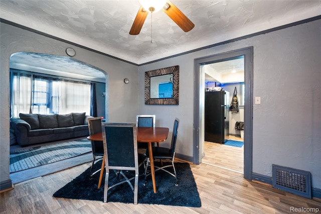 12518 Corbett St, Hamtramck, MI 48213 - dining area featuring arched walkways, wood finished floors, a ceiling fan, a textured wall, and baseboards