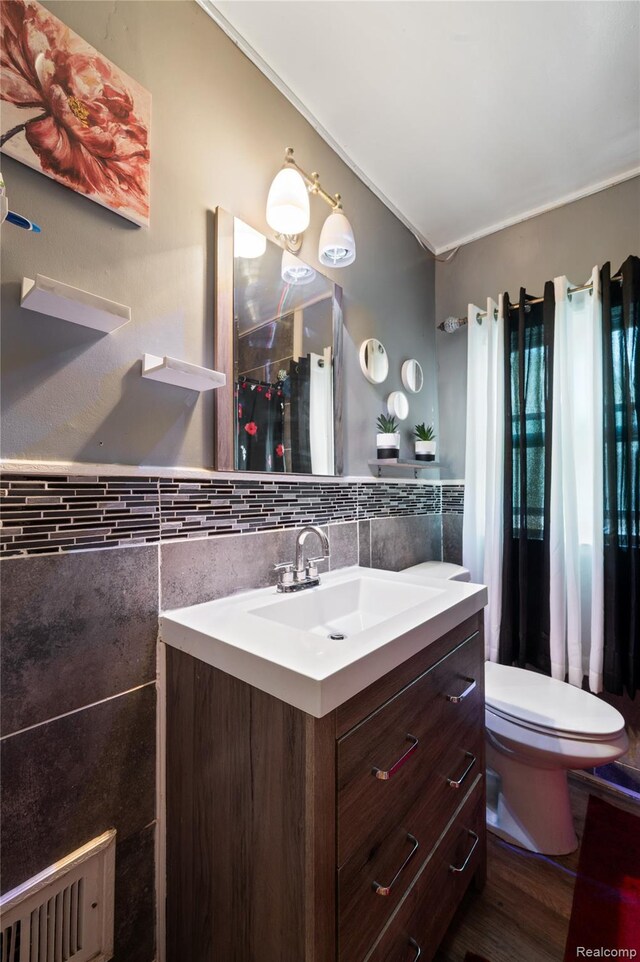 12518 Corbett St, Hamtramck, MI 48213 - bathroom featuring tile walls, vanity, toilet, a wainscoted wall, and wood finished floors