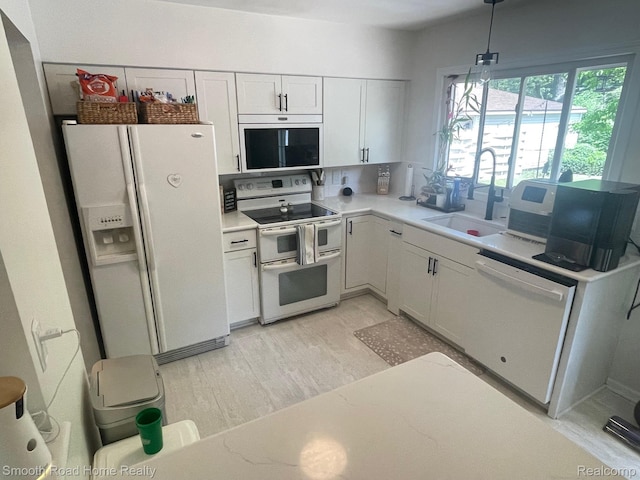 1525 Ackley Ave, Westland, MI 48186 - kitchen with white appliances, a sink, light countertops, white cabinets, and light wood-style flooring