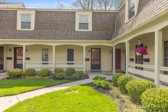 2463 Abbington Dr SE, Grand Rapids, MI 49506 - townhome / multi-family property with a shingled roof, a porch, mansard roof, and a front lawn