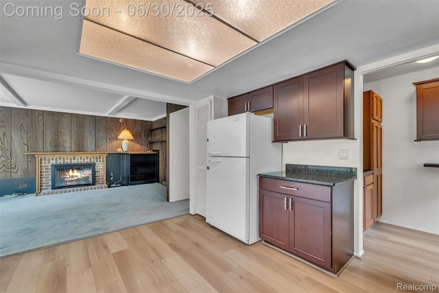 5772 Perrytown Dr, West Bloomfield, MI 48322 - kitchen with freestanding refrigerator, wood walls, light wood-style floors, a brick fireplace, and dark stone countertops