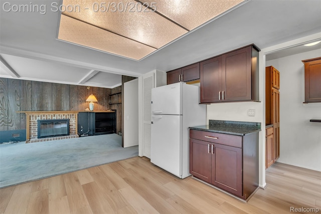 5772 Perrytown Dr, West Bloomfield, MI 48322 - kitchen featuring freestanding refrigerator, light wood-style flooring, a fireplace, wood walls, and dark stone counters