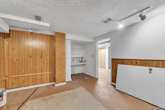 5772 Perrytown Dr, West Bloomfield, MI 48322 - unfurnished room with wooden walls, rail lighting, a textured ceiling, and concrete flooring