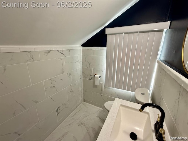 8419 Paige, Warren, MI 48089 - bathroom with marble look tile flooring, a sink, toilet, tile walls, and vaulted ceiling
