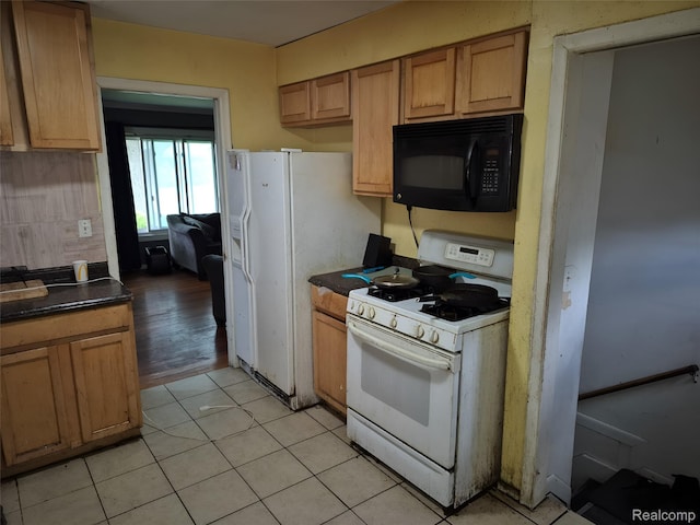 30102 Matthew St, Redford, MI 48186 - kitchen featuring white range with gas cooktop, black microwave, dark countertops, light tile patterned floors, and brown cabinets