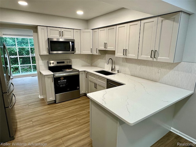 31404 Hunters Circle Dr, Farmington, MI 48334 - kitchen with stainless steel appliances, a sink, light stone counters, a peninsula, and tasteful backsplash