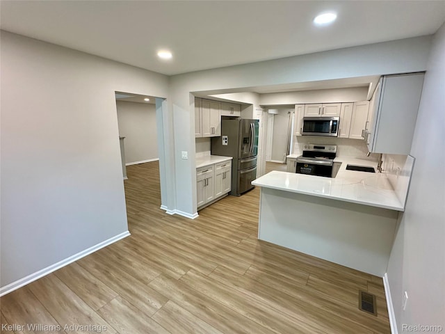 31404 Hunters Circle Dr, Farmington, MI 48334 - kitchen featuring appliances with stainless steel finishes, baseboards, light countertops, a sink, and a peninsula