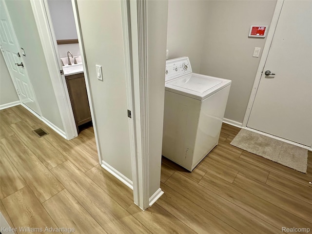 31404 Hunters Circle Dr, Farmington, MI 48334 - laundry room with washer / dryer, light wood-type flooring, and baseboards