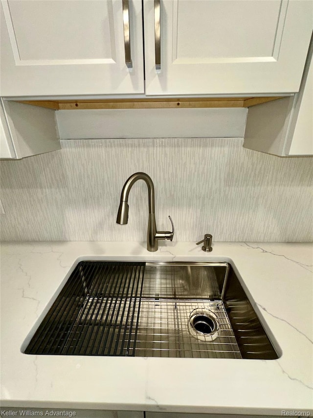 31404 Hunters Circle Dr, Farmington, MI 48334 - kitchen view of a sink, decorative backsplash, white cabinetry, and light stone counters