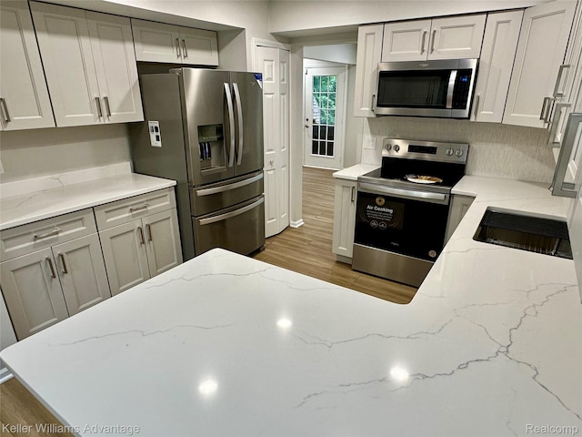 31404 Hunters Circle Dr, Farmington, MI 48334 - kitchen with stainless steel appliances, wood finished floors, light stone countertops, and gray cabinetry