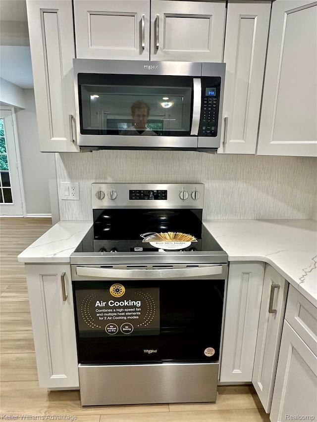 31404 Hunters Circle Dr, Farmington, MI 48334 - kitchen with stainless steel appliances, light wood-style flooring, light stone countertops, and white cabinets