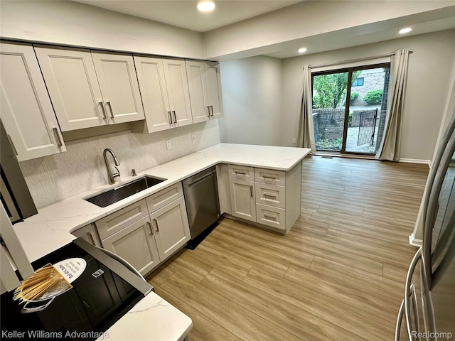 31404 Hunters Circle Dr, Farmington, MI 48334 - kitchen featuring dishwasher, a sink, a peninsula, backsplash, and light wood-style floors