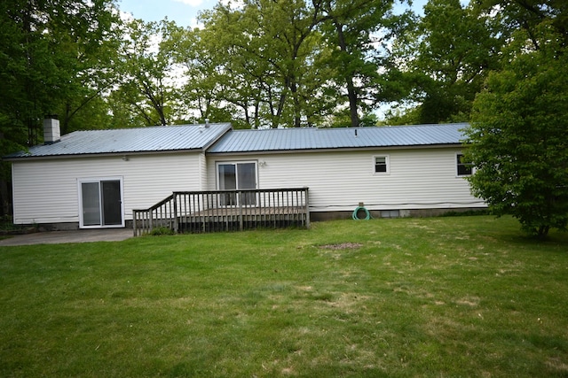 5830 Oneil St, Twin Lake, MI 49457 - back of property with a lawn, a wooden deck, a chimney, and metal roof