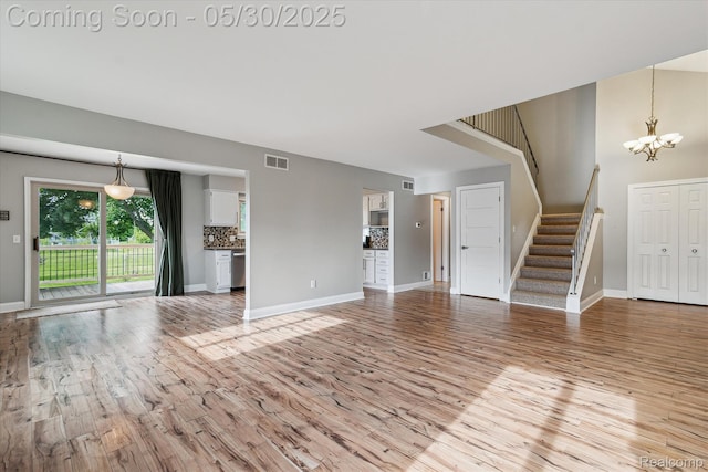 45127 Fair Oaks Dr, Canton, MI 48187 - unfurnished living room featuring light wood-type flooring, stairs, a chandelier, and baseboards