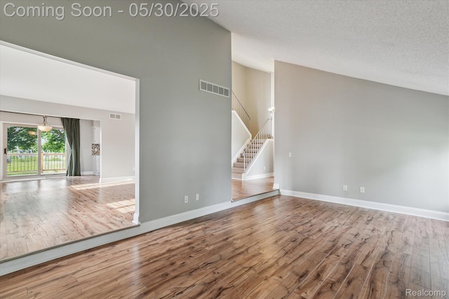 45127 Fair Oaks Dr, Canton, MI 48187 - spare room featuring high vaulted ceiling, wood finished floors, stairway, baseboards, and a textured ceiling