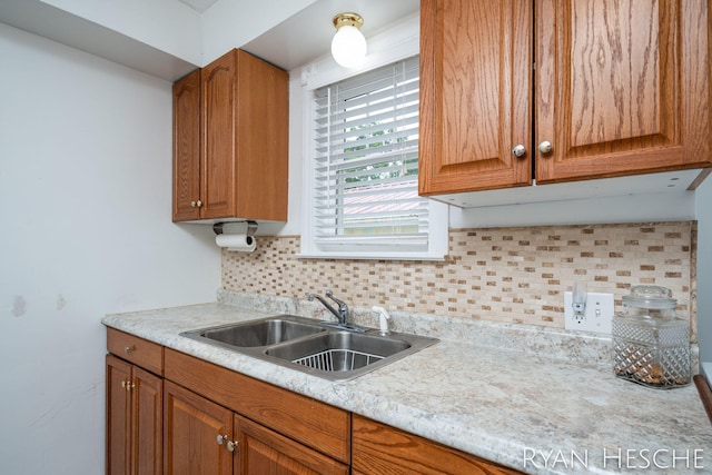 812 Forest St, Ionia, MI 48846 - kitchen featuring a sink, light countertops, decorative backsplash, and brown cabinetry