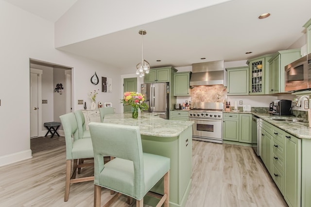 2210 Lindsey Rd, Jackson, MI 49201 - kitchen with green cabinetry, appliances with stainless steel finishes, wall chimney range hood, a sink, and a kitchen bar