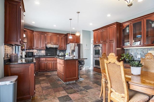 7340 Royal Ridge Dr SE, Caledonia, MI 49316 - kitchen with backsplash, dark stone finish flooring, recessed lighting, a kitchen island, and appliances with stainless steel finishes