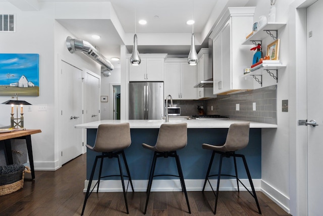 211 W Kingsley St, Ann Arbor, MI 48103 - kitchen with freestanding refrigerator, light countertops, a peninsula, backsplash, and dark wood-type flooring