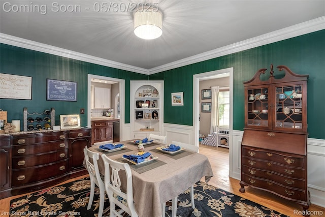 441 Mckinley Ave, Grosse Pointe Farms, MI 48236 - dining space with crown molding, built in shelves, light wood-style flooring, a decorative wall, and a wainscoted wall