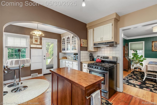 441 Mckinley Ave, Grosse Pointe Farms, MI 48236 - kitchen featuring stainless steel gas range oven, wooden counters, under cabinet range hood, arched walkways, and light wood-style floors