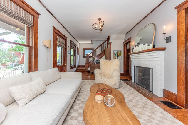 511 W Jefferson St, Ann Arbor, MI 48103 - living area with stairway, wood finished floors, a brick fireplace, baseboards, and crown molding